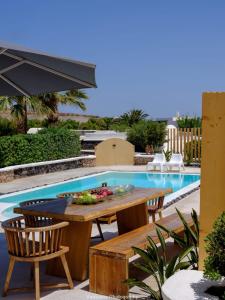 a table and chairs next to a swimming pool at Beautiful Santorini Villa 3 Bedrooms Villa Phos Private Pool and Lovely Sea View Exo Gialos in Karterados