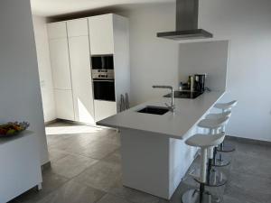 a kitchen with white cabinets and a sink and stools at Casa do Poço in Burgau