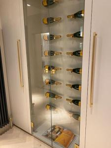 Luxury Georgian Apartment - 5 Minute Walk to Spa في باث: خزانة زجاجية مليئة بقوارير النبيذ