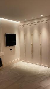 a room with white cabinets and a television on a wall at Luxury Georgian Apartment - 5 Minute Walk to Spa in Bath