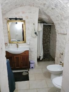 een badkamer met een wastafel, een toilet en een spiegel bij Country house GALLINARO in Castellana Grotte