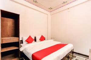 OYO Flagship 77120 Hotel Achrol Haveli Sukher في أودايبور: غرفة نوم بسرير ومخدات حمراء