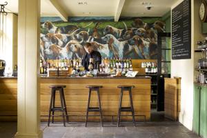 a bar in a restaurant with a mural of dogs at The Hare & Hounds Hotel in Tetbury