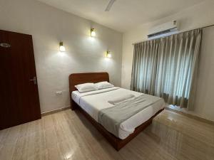 a bedroom with a large bed with white sheets and a window at Hotel Sandesh Palace Lonavala in Lonavala