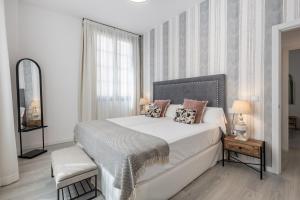 Un dormitorio con una gran cama blanca y una ventana en Apartamentos Puerta Elvira Suites 3000 en Granada
