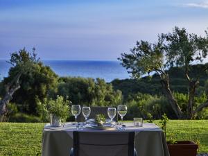 a table with wine glasses and the ocean in the background at Leivatho Hotel in Svoronata
