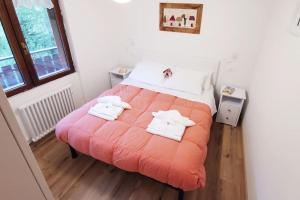 a bedroom with a large orange bed with towels on it at Casina Alpina sugli impianti Passo S Pellegrino in Passo San Pellegrino