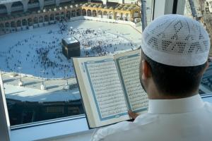 un homme regarde par une fenêtre un grand bâtiment dans l'établissement Swissotel Makkah, à La Mecque