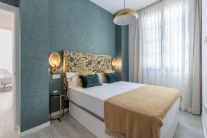 ein Schlafzimmer mit einem Bett und einer blauen Wand in der Unterkunft Apartamentos Albaicín Centro Suites 3000 in Granada