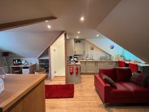 a living room with a red couch and a kitchen at 1 Bed Studio - Sleeps 2 - Wifi - Parking in Pitlochry