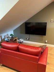 un divano rosso in un soggiorno con TV a schermo piatto di Inviting 1-Bed Studio in Pitlochry a Pitlochry