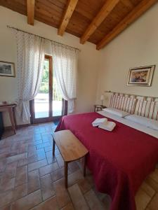 sypialnia z dużym czerwonym łóżkiem i stołem w obiekcie Casale Terre Rosse Garden w mieście Saturnia