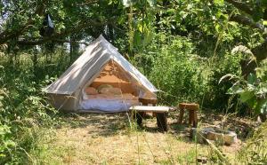 uma pequena tenda com uma cama na relva em Camp Golstav - Romantic view over the hills. em Flobecq