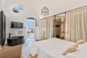 a bedroom with a tub and a bed and a tv at Arya Nobile Dimora in Carovigno