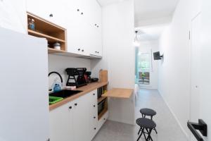 a kitchen with white cabinets and a sink and two stools at Aiolos kolonaki vip apartment in Athens