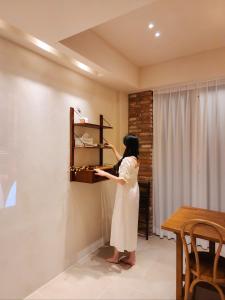 Una mujer está llegando a un estante en una habitación en Poolvilla Gaon, en Busan