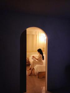 a woman in a white dress sitting on a bed at Poolvilla Gaon in Busan