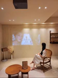 Kobieta siedząca na krześle oglądająca film w obiekcie Poolvilla Gaon w Pusanie