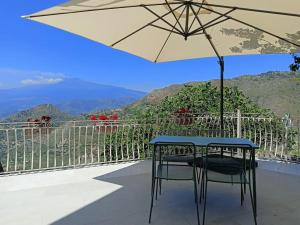 a table and a chair with an umbrella on a balcony at Stanza Mylai Etna View in Castelmola