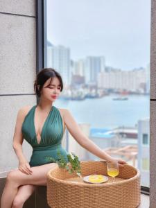 una mujer con un vestido verde sentada en una mesa con una copa de vino en Poolvilla Gaon, en Busan