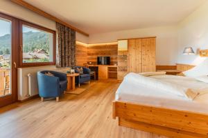 a hotel room with a bed and two chairs at Wiesenhof, Hotel direkt am See in Weissensee