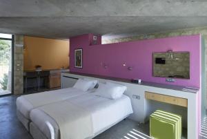 a bedroom with a white bed with a pink wall at Leivatho Hotel in Svoronata