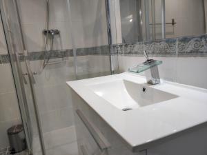 La salle de bains blanche est pourvue d'un lavabo et d'une douche. dans l'établissement Top30 Precioso ático con terraza 1A104, à Gijón