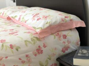a bed with a pillow with pink flowers on it at Casa Ilaria in Armeno