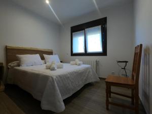 Schlafzimmer mit einem Bett, einem Fenster und einem Stuhl in der Unterkunft Apartamentos Sierra y Mar Aldealengua de Pedraza in Ceguilla