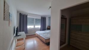 1 dormitorio con cama, escritorio y ventana en Ferienwohnung Friedenau, en Steinfurt