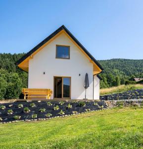 a white house with a bench on a hill at Domek pod Magurką in Międzybrodzie Bialskie