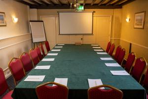 a conference room with a long table and red chairs at Cross Hands Hotel by Greene King Inns in Yate