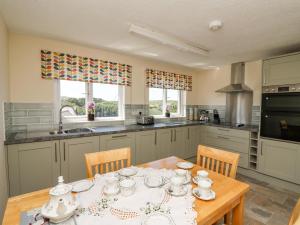 uma cozinha com uma mesa e cadeiras de madeira e uma cozinha com uma mesa e cadeiras em 2 Sunny Hill em Haverfordwest