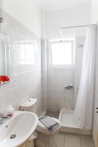 biała łazienka z umywalką, toaletą i wanną w obiekcie Kalami Rooms w mieście Falasarna