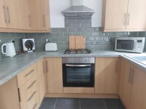 a kitchen with a stove and a microwave at Charming 2 BedRoom Tredegar Gem. Sleeps 4 in Tredegar