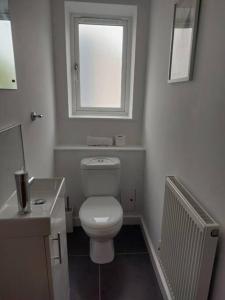 a white bathroom with a toilet and a window at Charming 2 BedRoom Tredegar Gem. Sleeps 4 in Tredegar