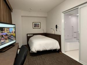 um quarto com uma cama e uma televisão de ecrã plano em Hotel Alpha-One Kitashinsaibashi em Osaka