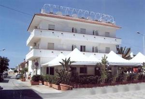 um grande edifício branco com guarda-chuvas brancos em frente em Hotel Noto Marina e Spa em Noto Marina