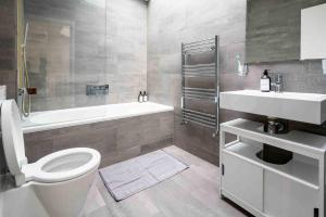 La salle de bains est pourvue de toilettes, d'une baignoire et d'un lavabo. dans l'établissement Stunning 3-Bed House in central London, à Londres