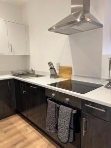 a kitchen with a sink and a stove top oven at Sleek & Stylish Apartment by DH ApartHotels in Peterborough