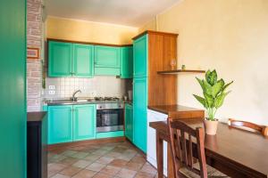 une cuisine avec des placards verts et une table en bois dans l'établissement [Lago Trasimeno 15 min.] Casa con A/C e Wi-Fi, à Agello