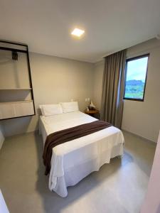 a bedroom with a large white bed with a window at Beach class Muro Alto 3202 in Porto De Galinhas