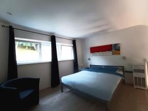 1 dormitorio con 1 cama y 2 ventanas en Le Havre du Circuit / Triplex avec Sauna en Malmedy