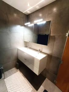 y baño con lavabo blanco y espejo. en Le Havre du Circuit / Triplex avec Sauna en Malmedy