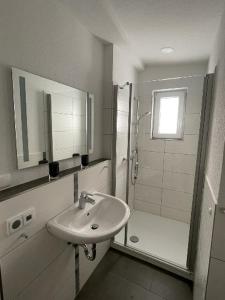 uma casa de banho branca com um lavatório e um chuveiro em Ferienwohnung Pirna mit Elbblick em Pirna