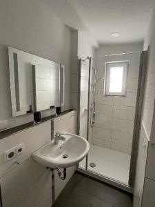 a white bathroom with a sink and a shower at Ferienwohnung Pirna mit Elbblick in Pirna