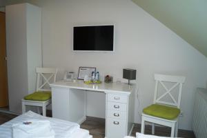 a room with a desk with two chairs and a tv at REGIOHOTEL Aparthotel Wernigerode in Wernigerode