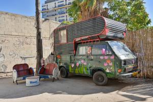 a bus is parked next to a wall at Caravan Hostel Tel Aviv By Roger Age 18-45 in Tel Aviv