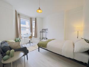 a white bedroom with a large bed and a couch at Leyton House - SleepyLodge in London