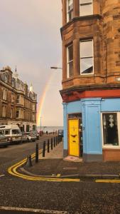 un arco iris en el cielo sobre una calle con un edificio en Portobello Charming Seaside 3-BR Holiday Apartment en Edimburgo